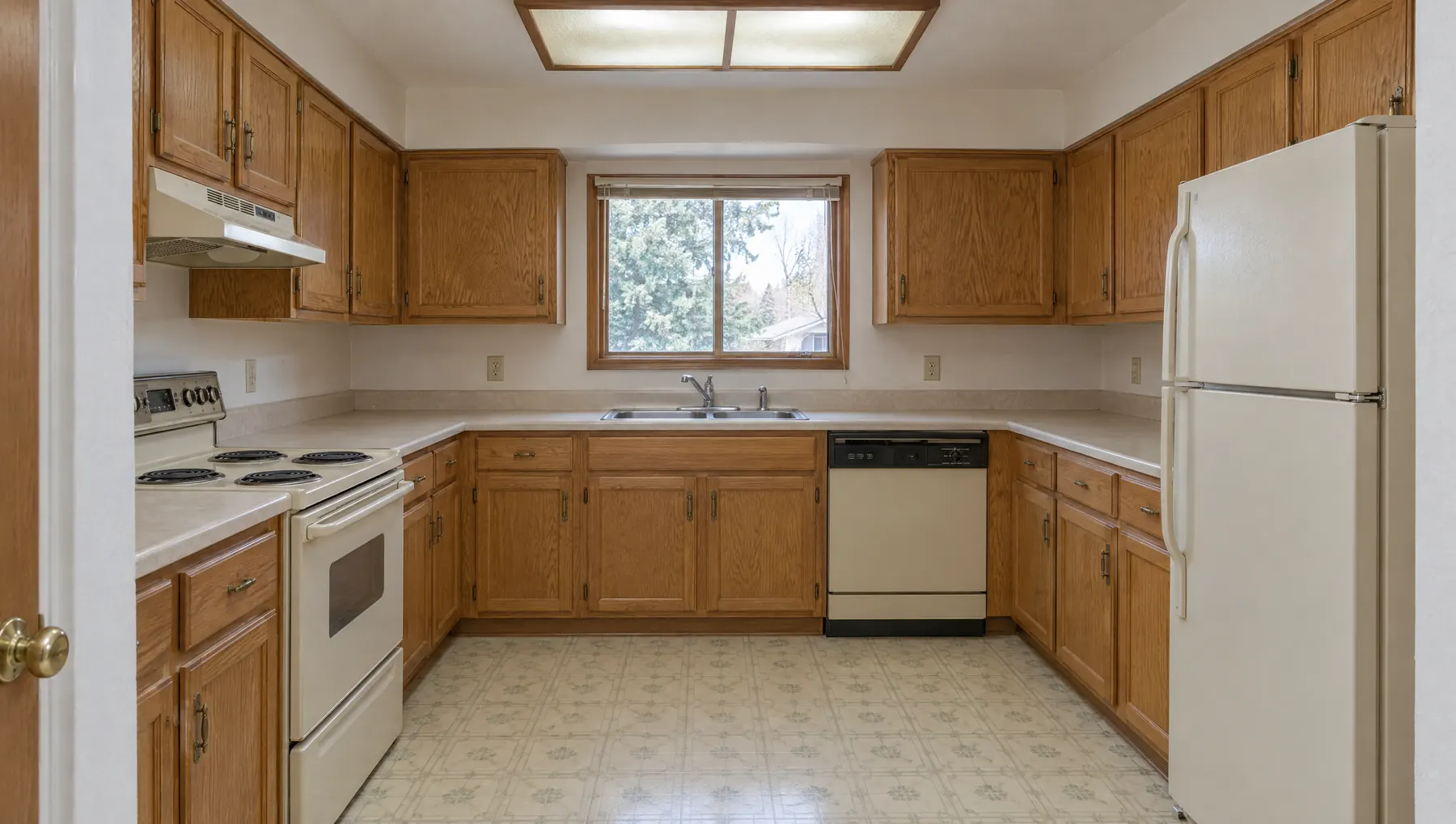 The same kitchen before the remodel, with dated oak cabinets and laminate counters