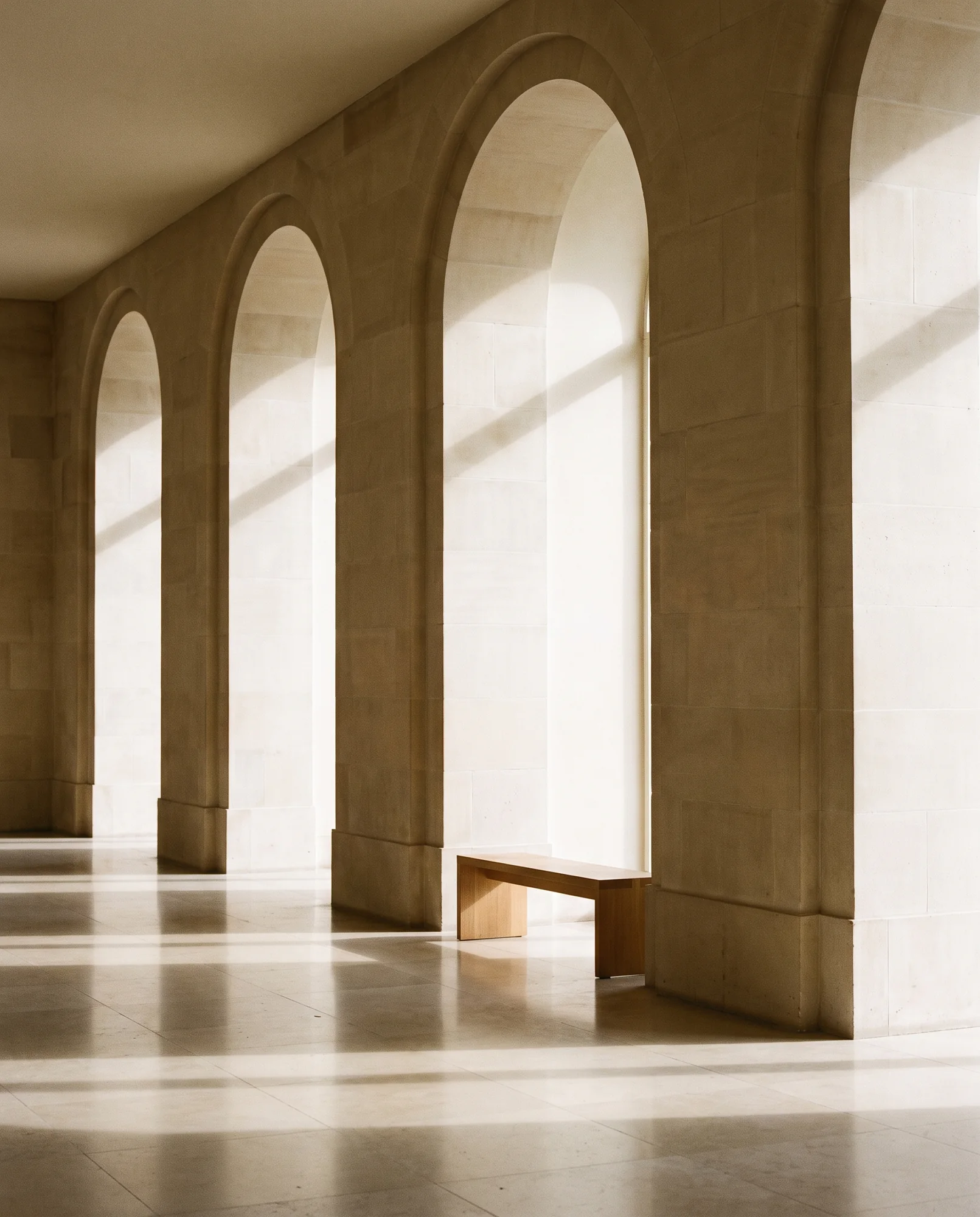 A limestone room with tall arches and light shafts